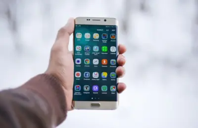 Close-up of a hand holding a Samsung smartphone displaying various app icons, emphasizing technology and connectivity.