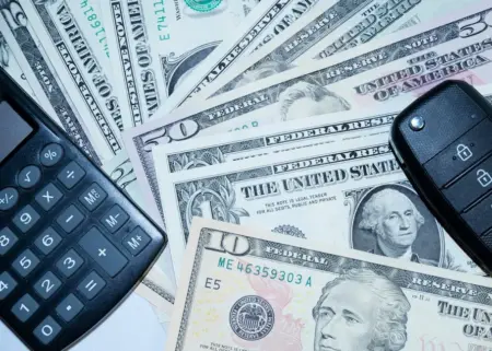 US dollars, calculator, and car keys representing finance and investment tools.