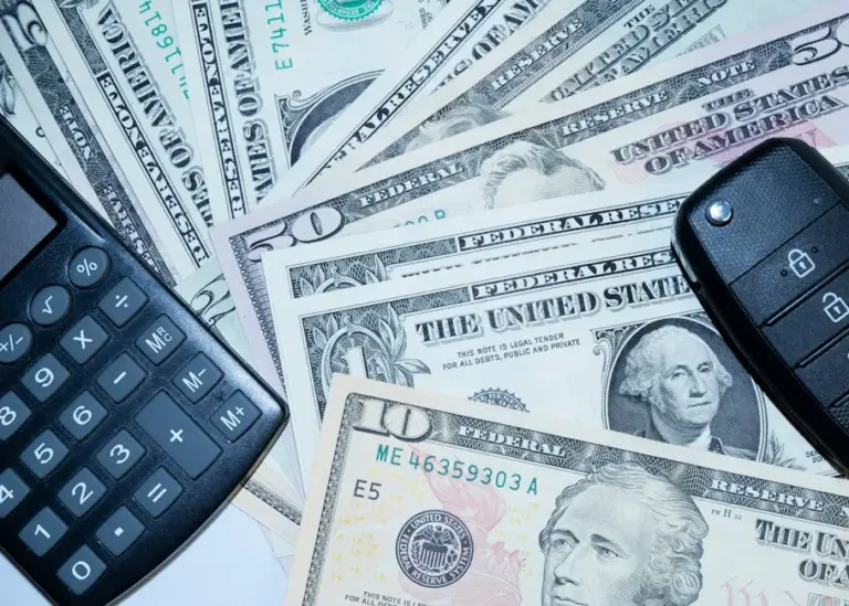 US dollars, calculator, and car keys representing finance and investment tools.