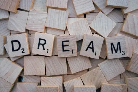 Idade Mental: O Que Isso Revela Sobre Você Em 2026! Close-up of wooden Scrabble tiles spelling the word 'DREAM', symbolizing creativity and imagination.